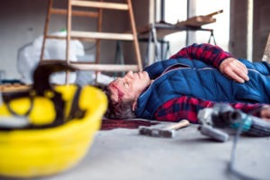 A worker lying on the floor after a fall from a ladder