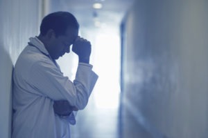 regretful-doctor-standing-in-a-dark-hallway